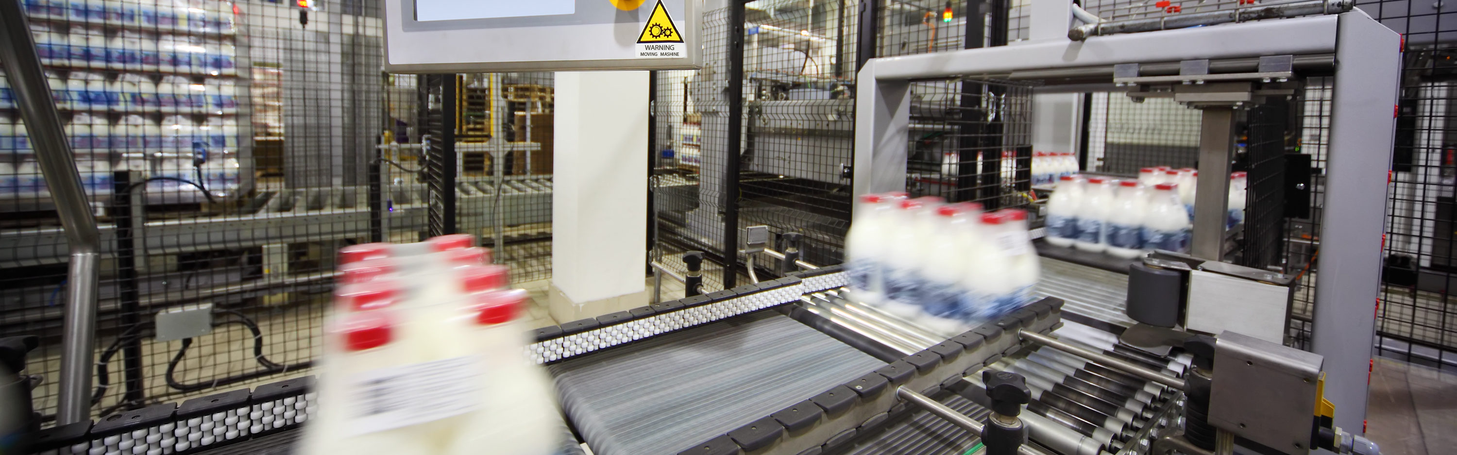 Conveyor with wrapped milk bottles at big factory; display of control computer